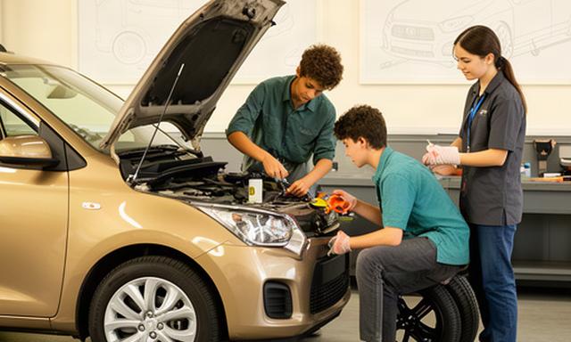 Young drivers learning to check engine oil and tire pressure at a local car care clinic